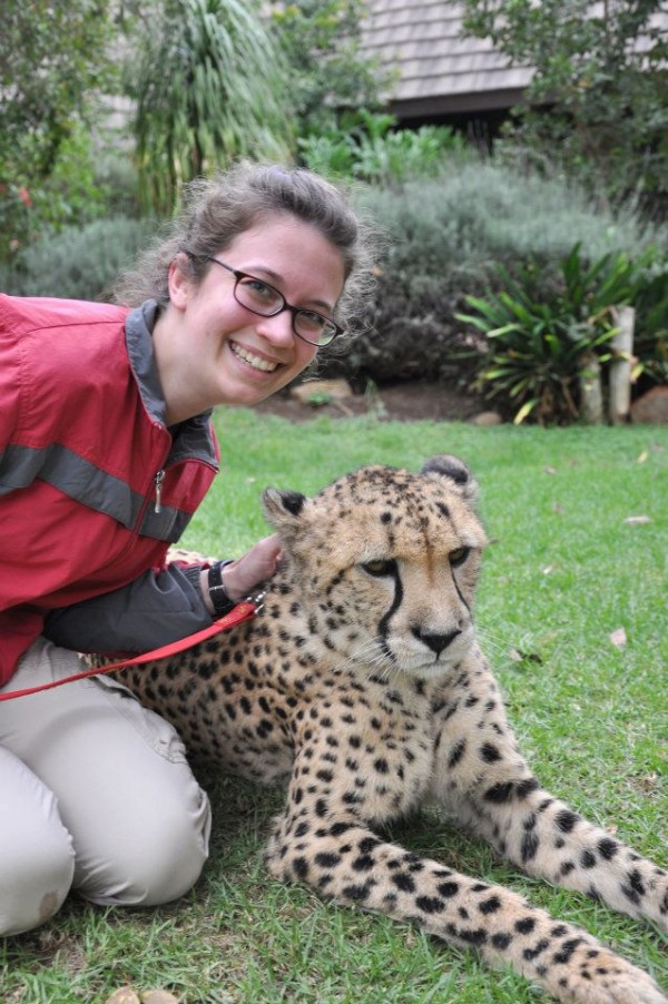A woman poses beside a cheetah
