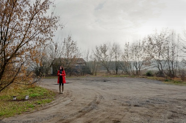 A woman in a red coat on the side of the road