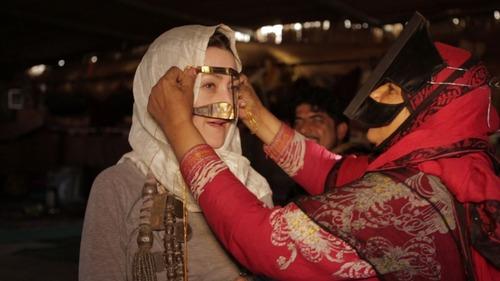 In Oman, they call the face mask a burqa. Sampta, a very traditional Bedouin woman, helps Froelich test it out. (Andrew Rothschild)