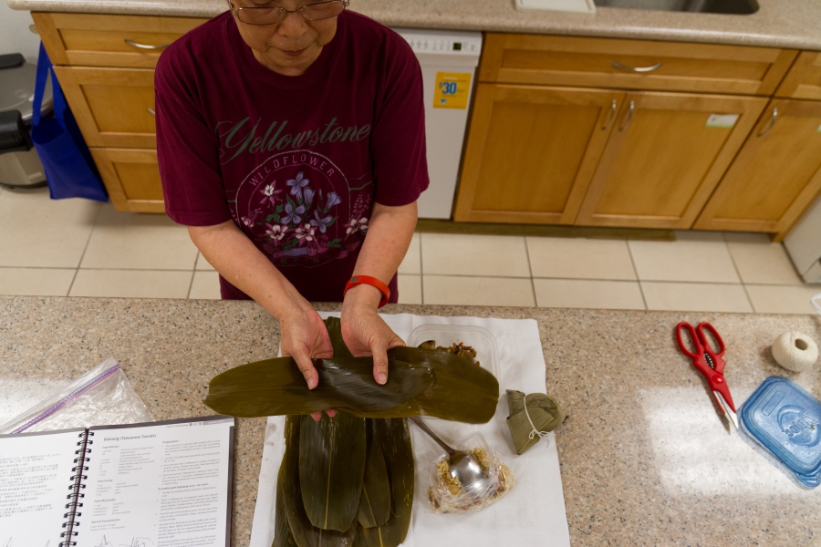 Photo: Julie Yu of Milpitas demonstrates how to layer bamboo leaves to make bah tsang, Taiwanese rice dumplings, for the Dragon Boat Festival.  pri.org Credit: Grace Hwang Lynch