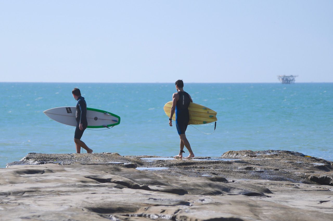 Surfers entering water at Piscinas Peru