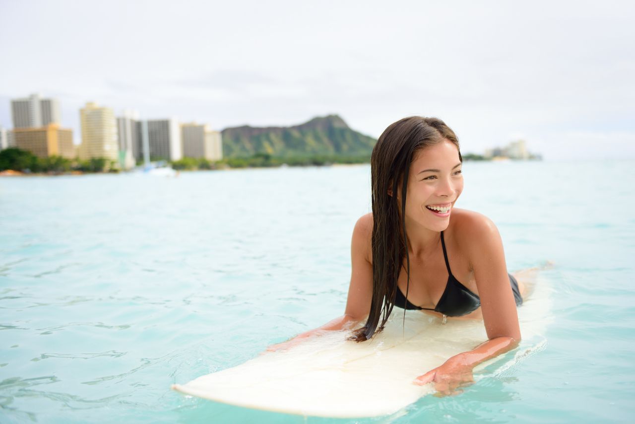 Woman lying on surfboard in Waikiki