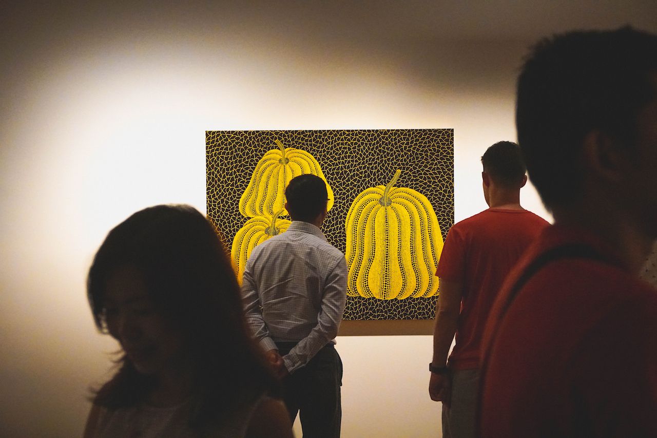A visitor looking at one of Yayoi Kusama's exhibit