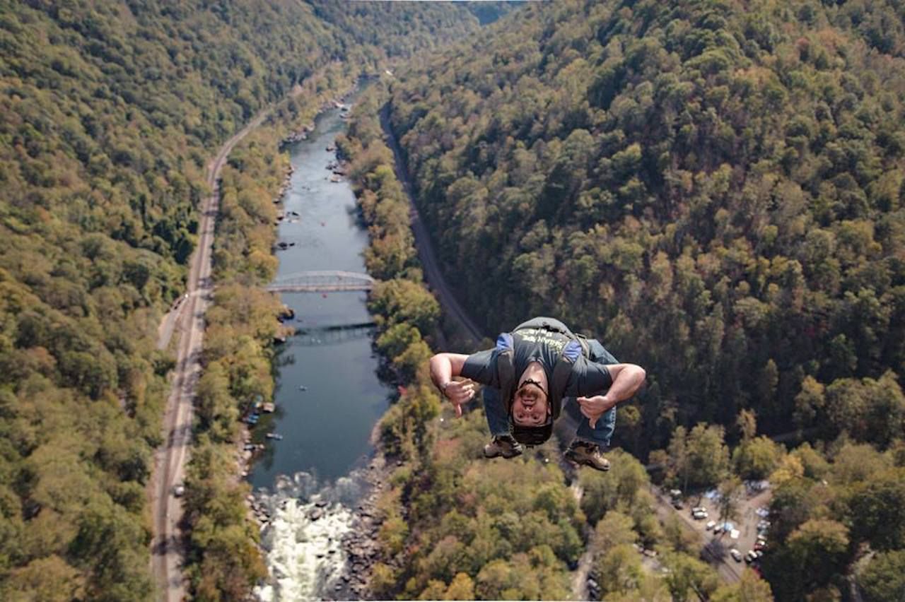 Aerial view of base jumper suspended over river on Bridge Day
