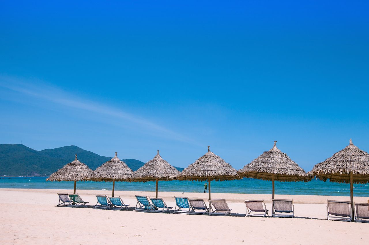 Beach umbrellas and deck chairs in front of the My Khe beach in Da Nang, Vietnam
