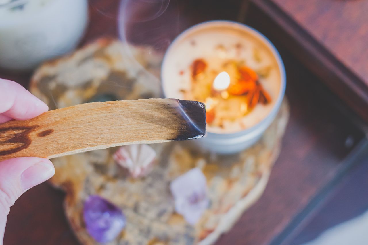 Burning palo santo with candle and gemstones