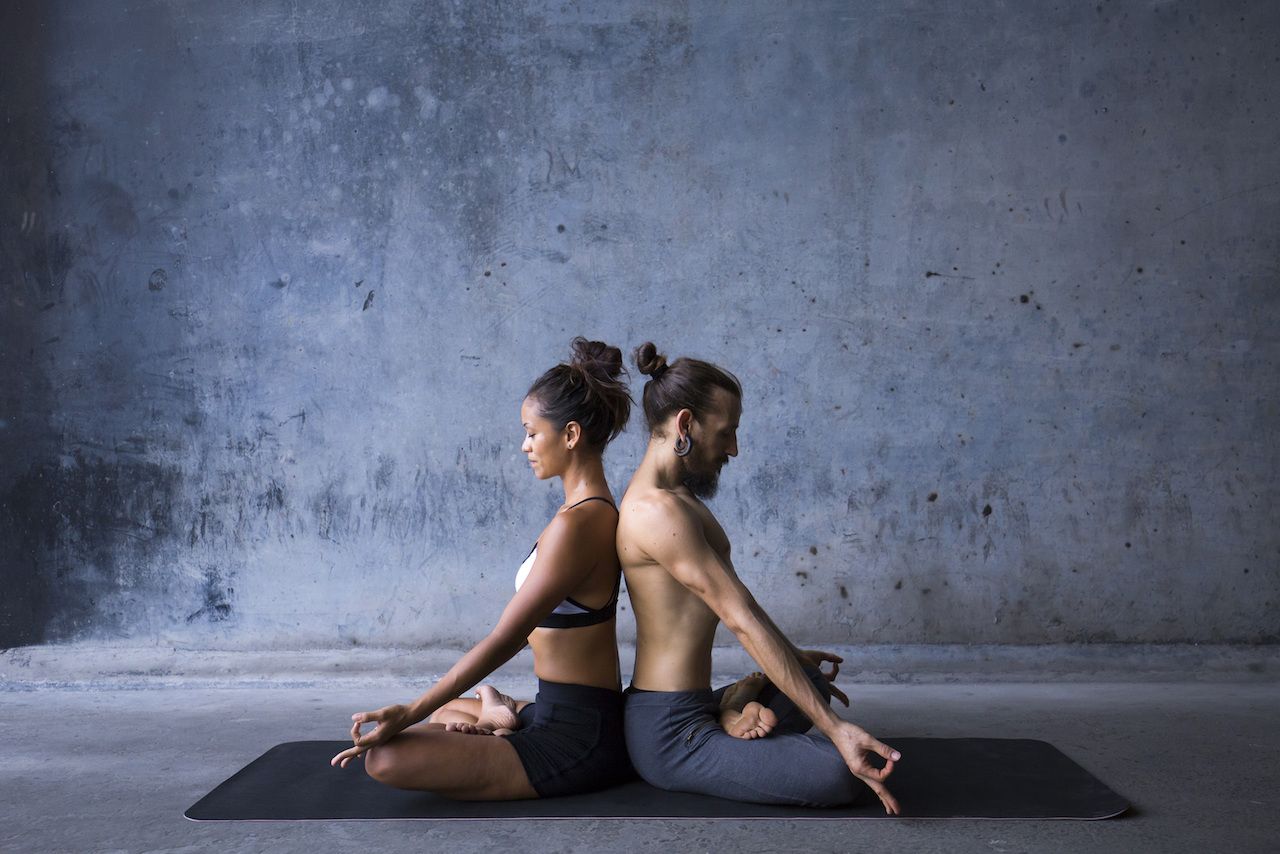 Young couple meditating together, sitting back to back