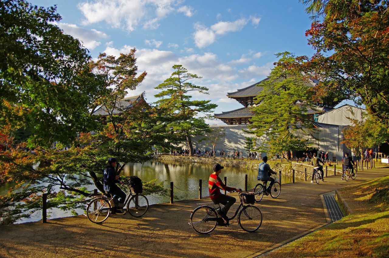 Cyclists at the Todai-ji Temple in Japan under blue skies