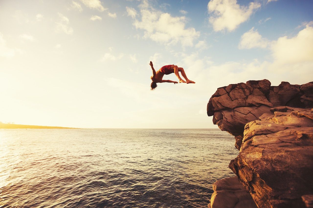 Man jumping from a cliff into the ocean