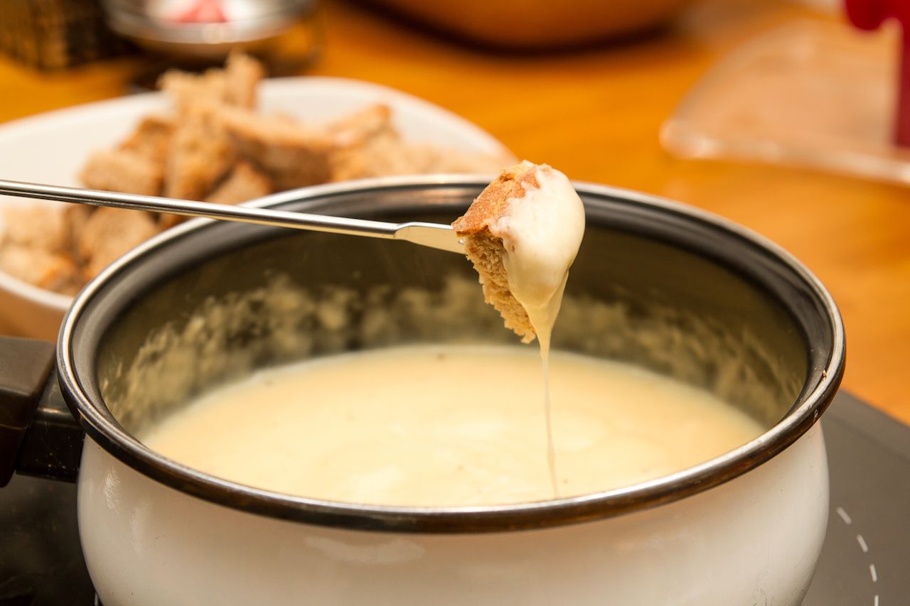 Pot of cheese fondue with dipping bread on skewer