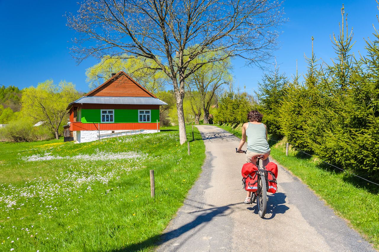 Young woman rides a bike on country road in spring time in the Banica village, Poland
