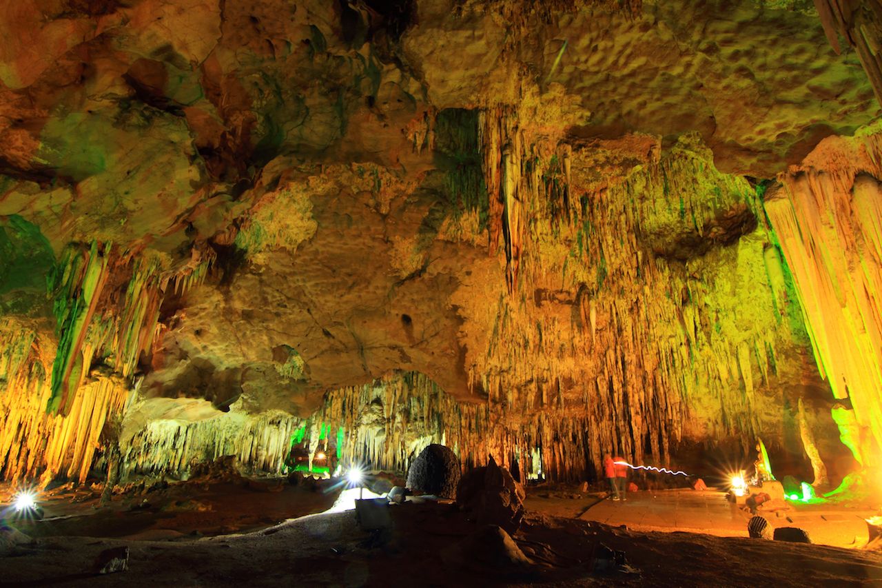 stalagmite and stalactite lit with colored lights in a cave