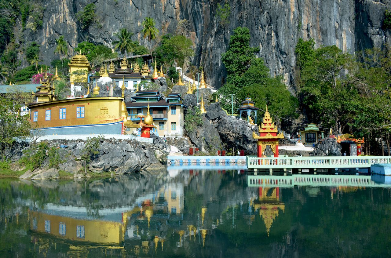 Buddhist monastery and lots of golden stupas reflecting in the water of the sacred lake in Hpa-an, Myanmar