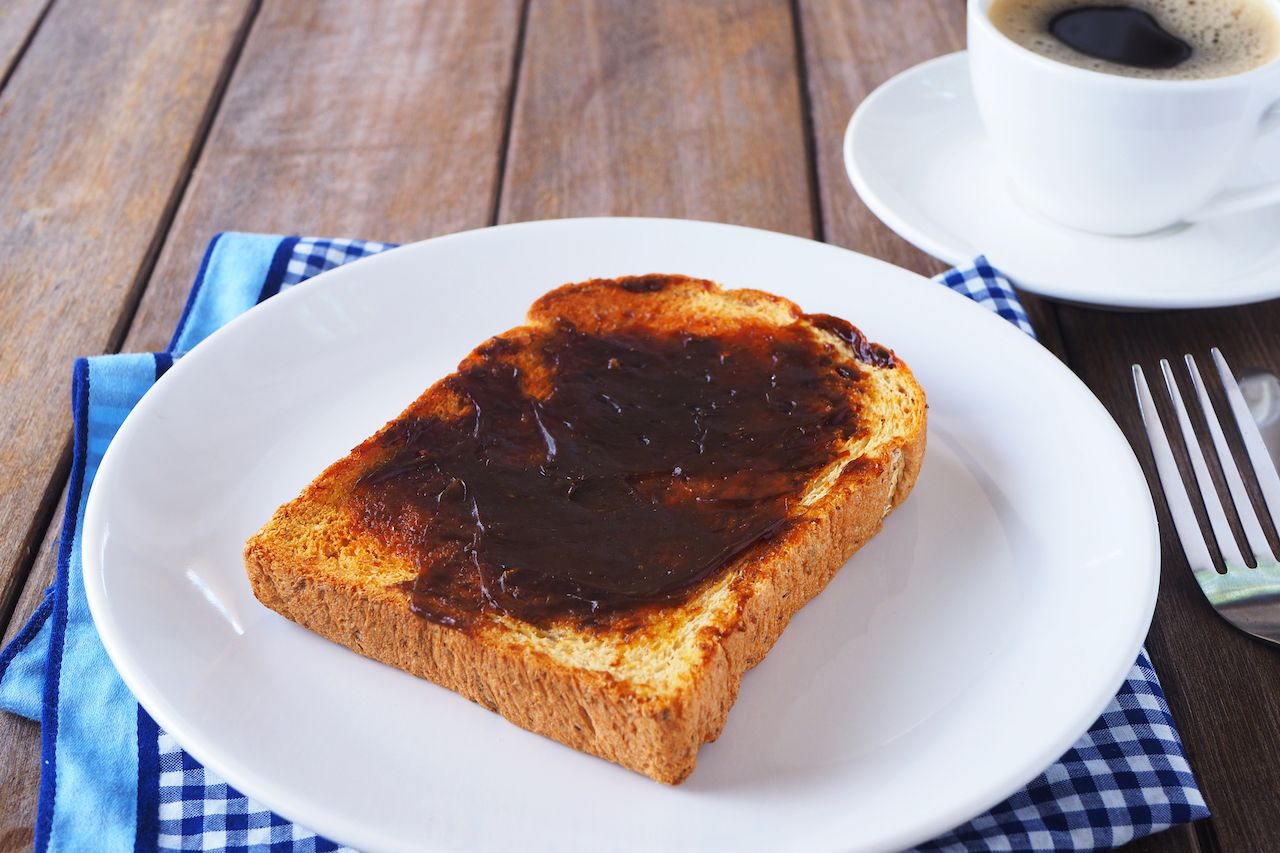 Close up of Australian breakfast with vegemite spread on a sliced wholewheat toast on a wooden table