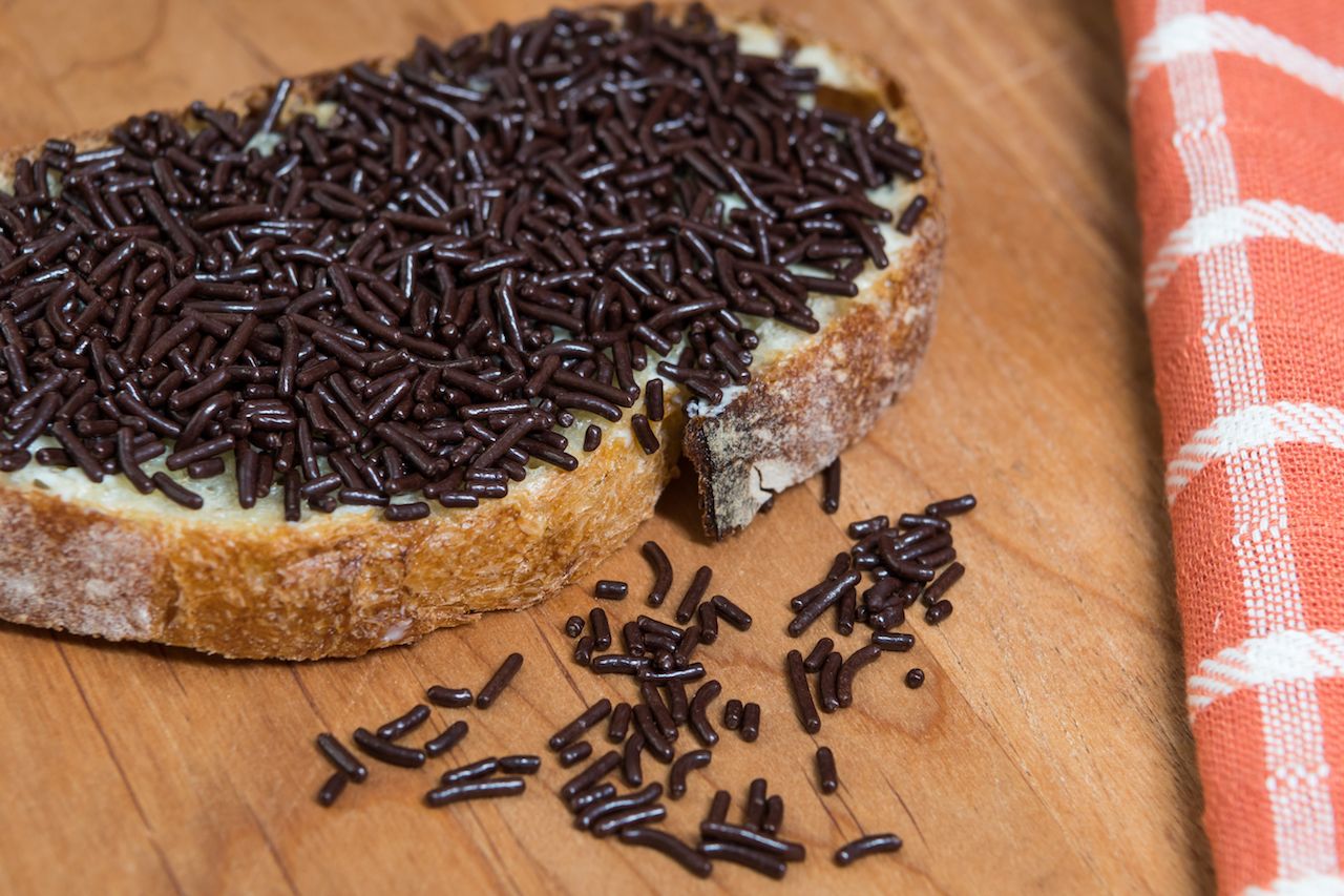 Close up of Chocolate Sprinkles Fallen off of Bread onto wooden board