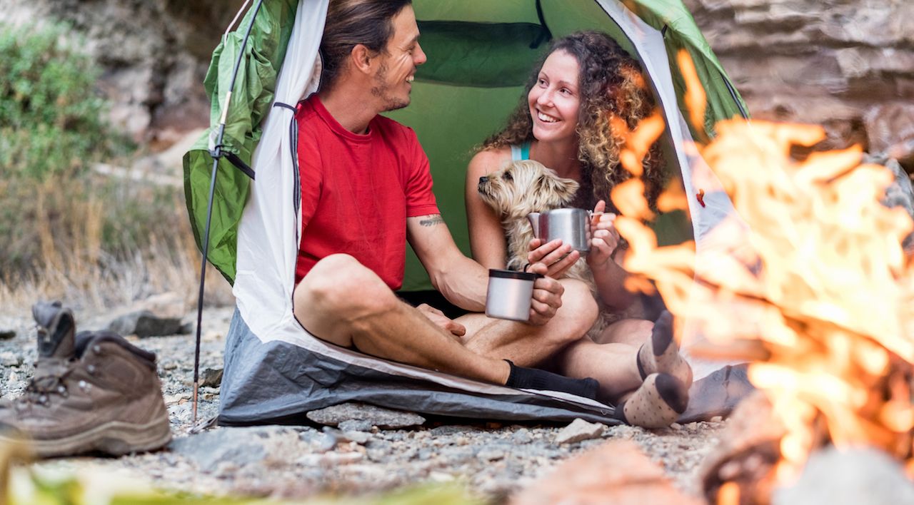 couple camping in rock mountains with their dog