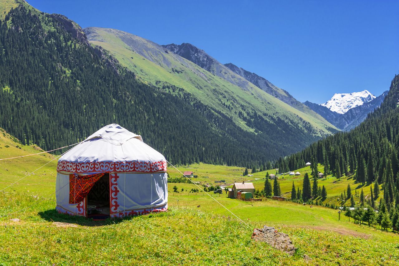 Beautiful mountain landscape with a white yurt, decorated with a red ornament, in Kyrgyzstan