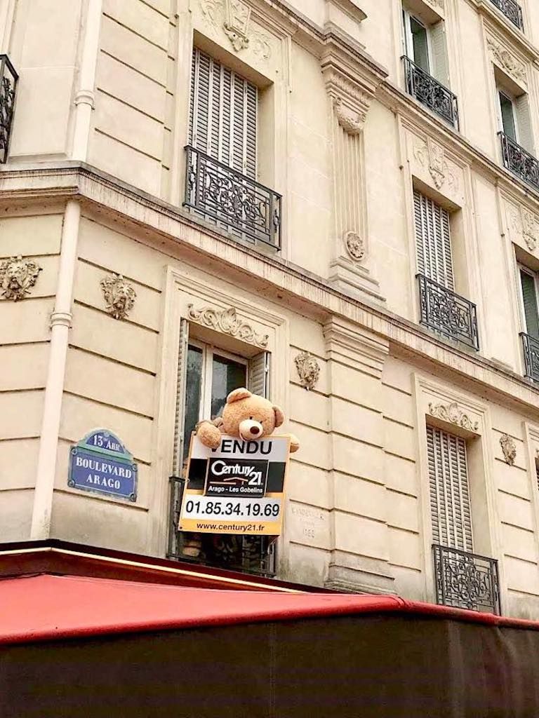Giant teddy bear sticking its head out of an apartment window in Paris