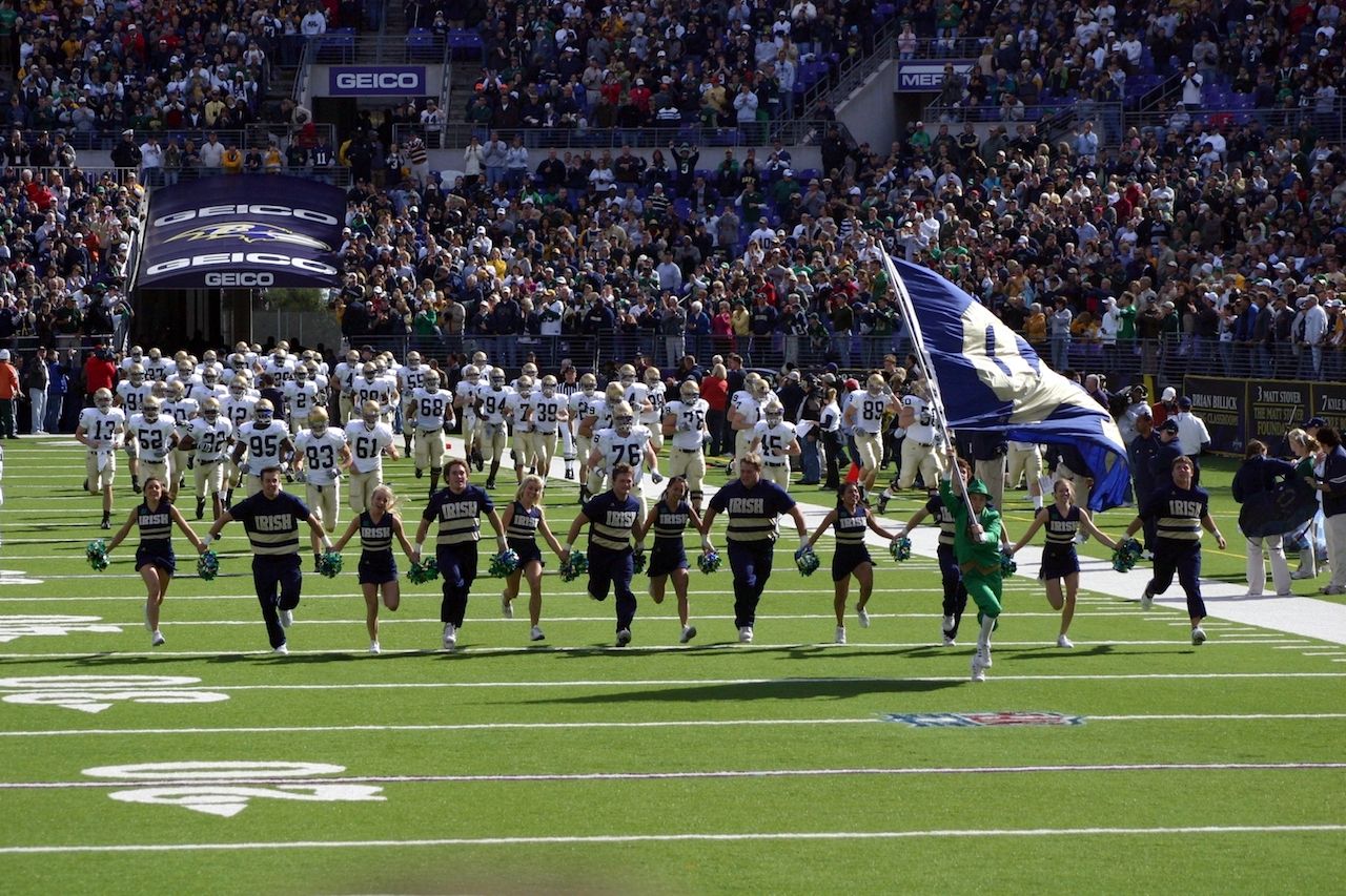 Notre Dame cheerleaders, coaches, and players take the field