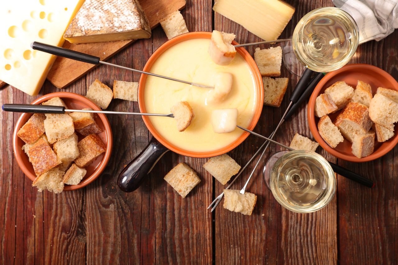 Pot of fondue with bread and cheese on a table