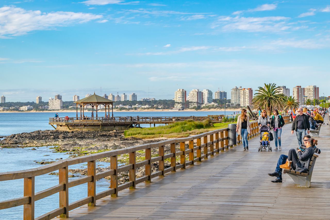 People at sunny winter at waterfront boardwalk in Punta del Este city, Uruguay