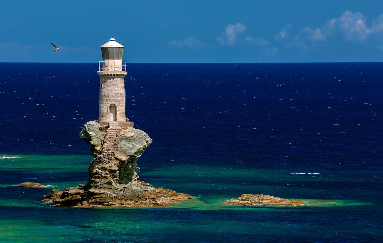 The beautiful Lighthouse Tourlitis of Chora in Andros Island and a Seagull, Cyclades, Greece
