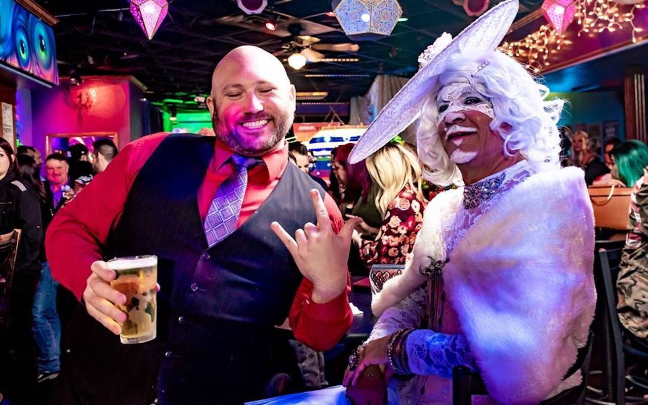 Two men, one in drag, enjoying themselves at a gay bar party