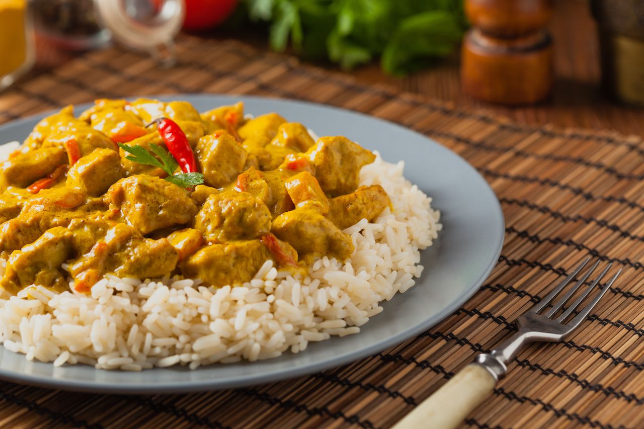 Yellow chicken curry over rice with red pepper garnish