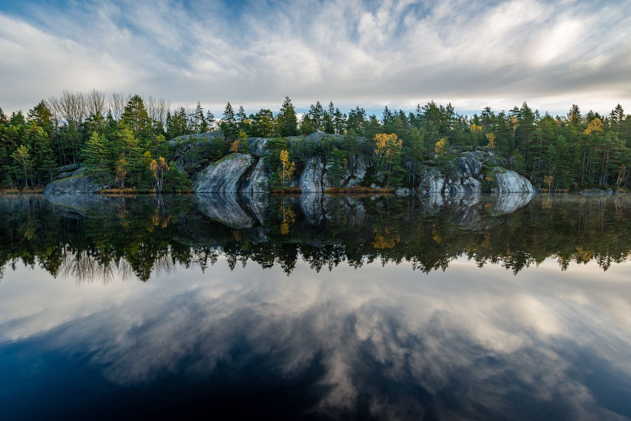 Forest and cliffs mirrored in calm lake