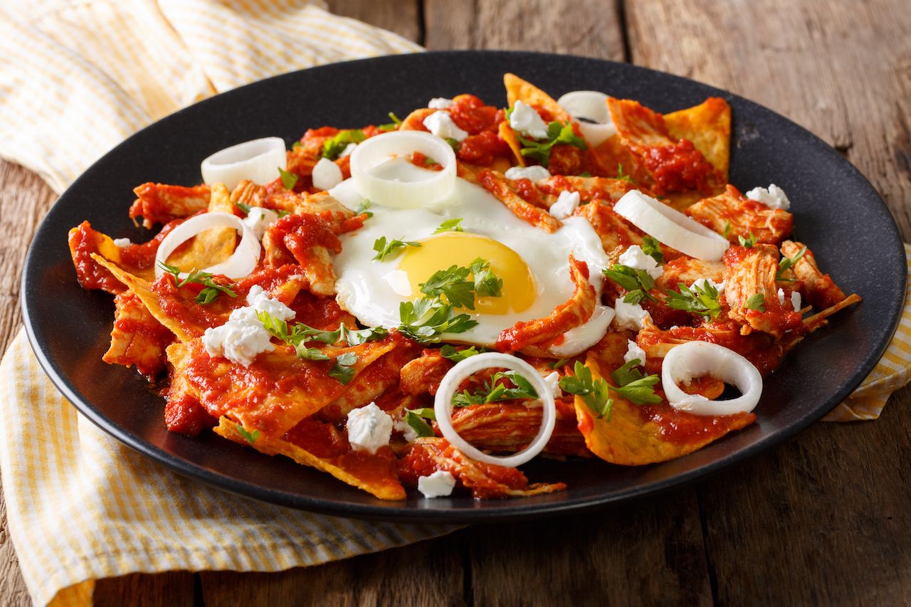 Mexican nachos with tomato salsa, chicken and egg close-up on a plate
