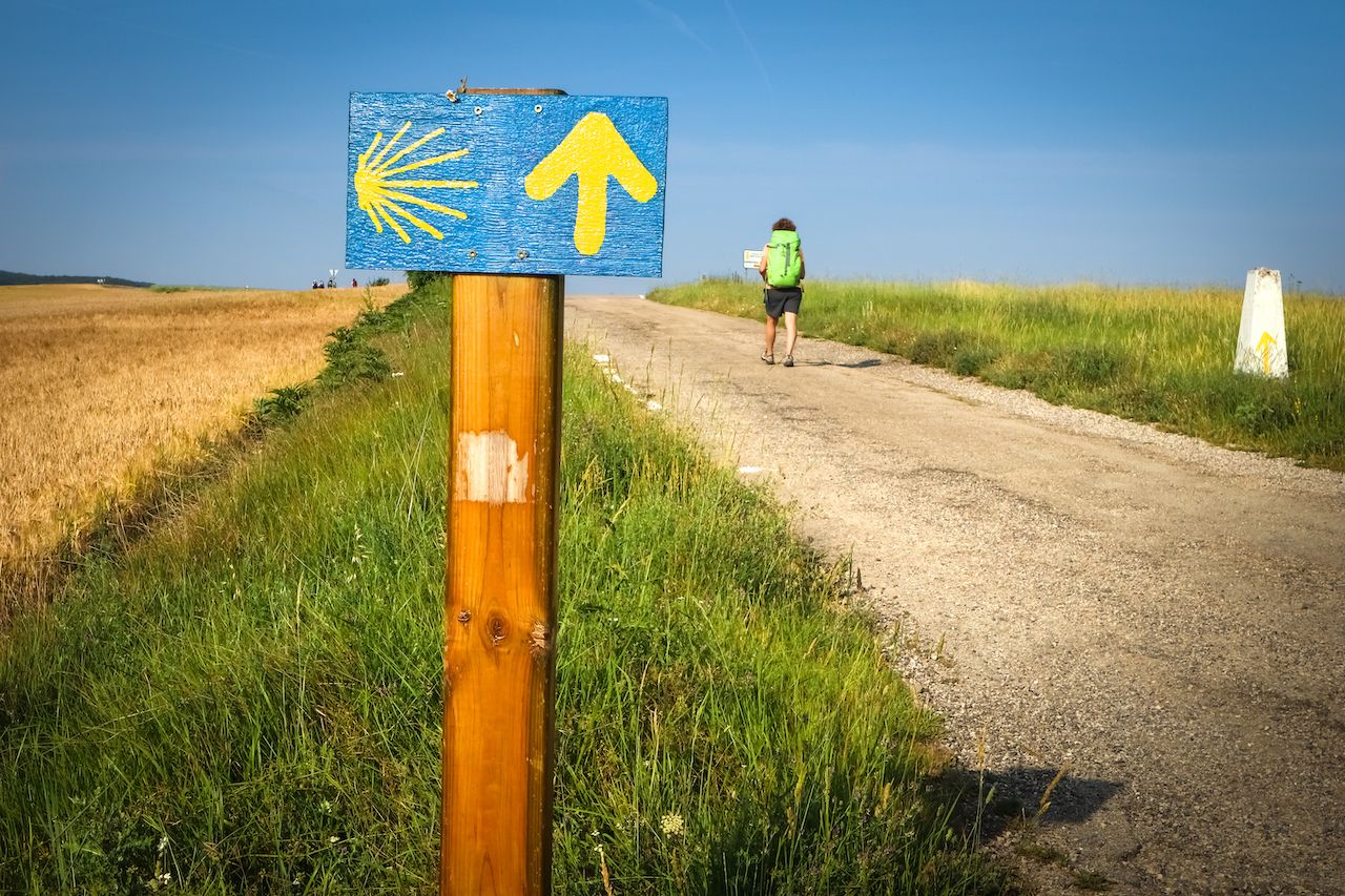 Milemarker and hiker on the Camino de Santiago