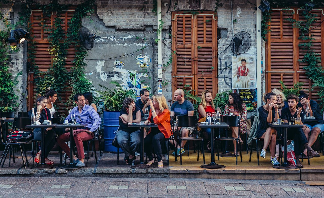 People sits at tables outside the restaurant at Rothschild Boulevard in Tel Aviv