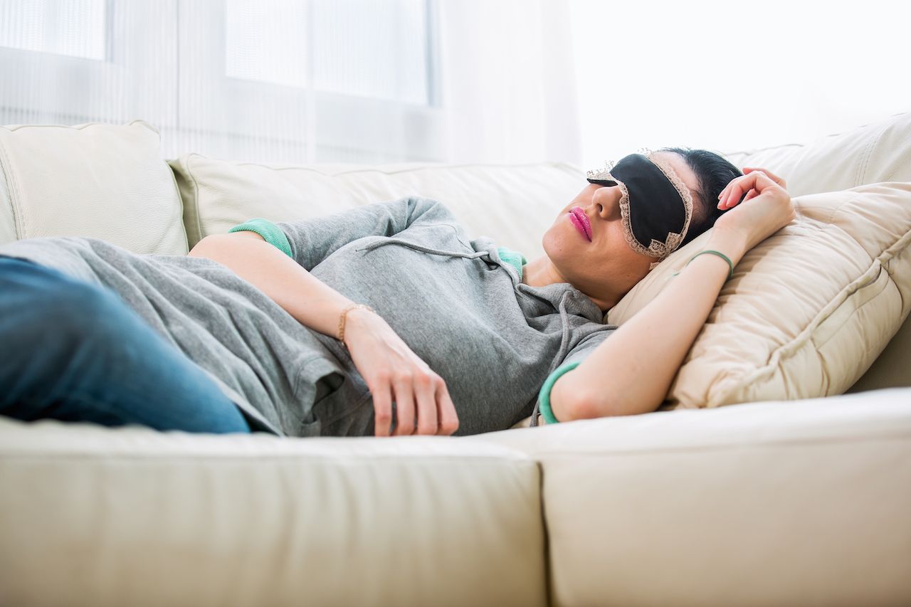 Person with an eyemask sleeping on a couch