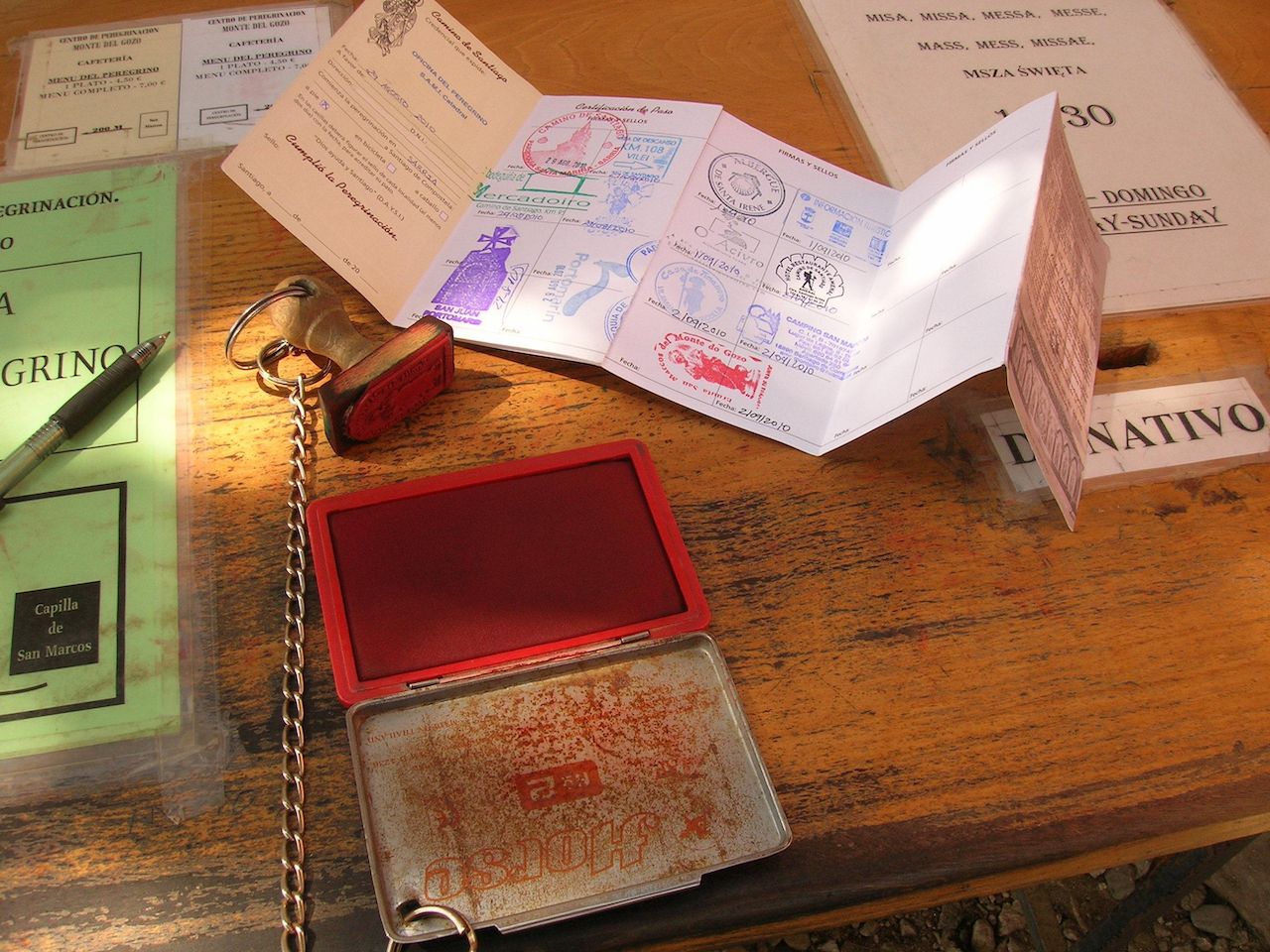 Pilgrim identification named Compostelana over a wooden table with stamp and red ink