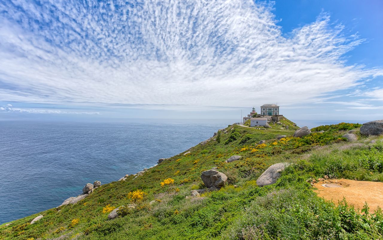 View of Cape Finisterre, Galicia, Spain with the lighthouse under a cloudy blue sky