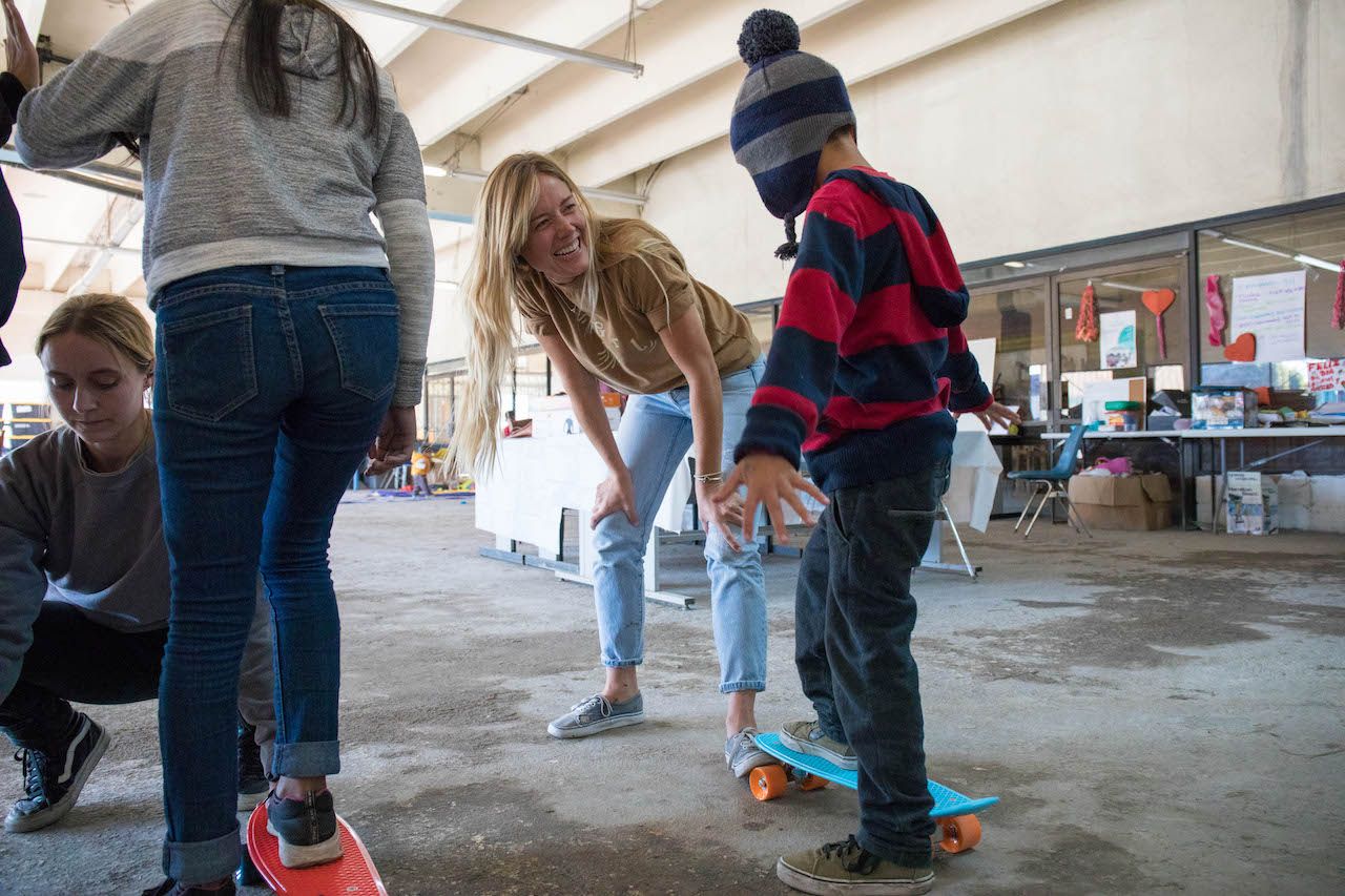 Female skateboarders teaching skateboarding to Mexican migrant kids