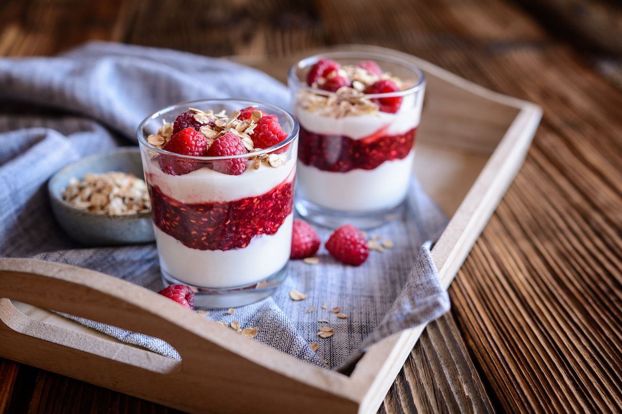 two cups of Cranachan on a wooden platter with strawberries, raspberries, and oats-Scottish foods