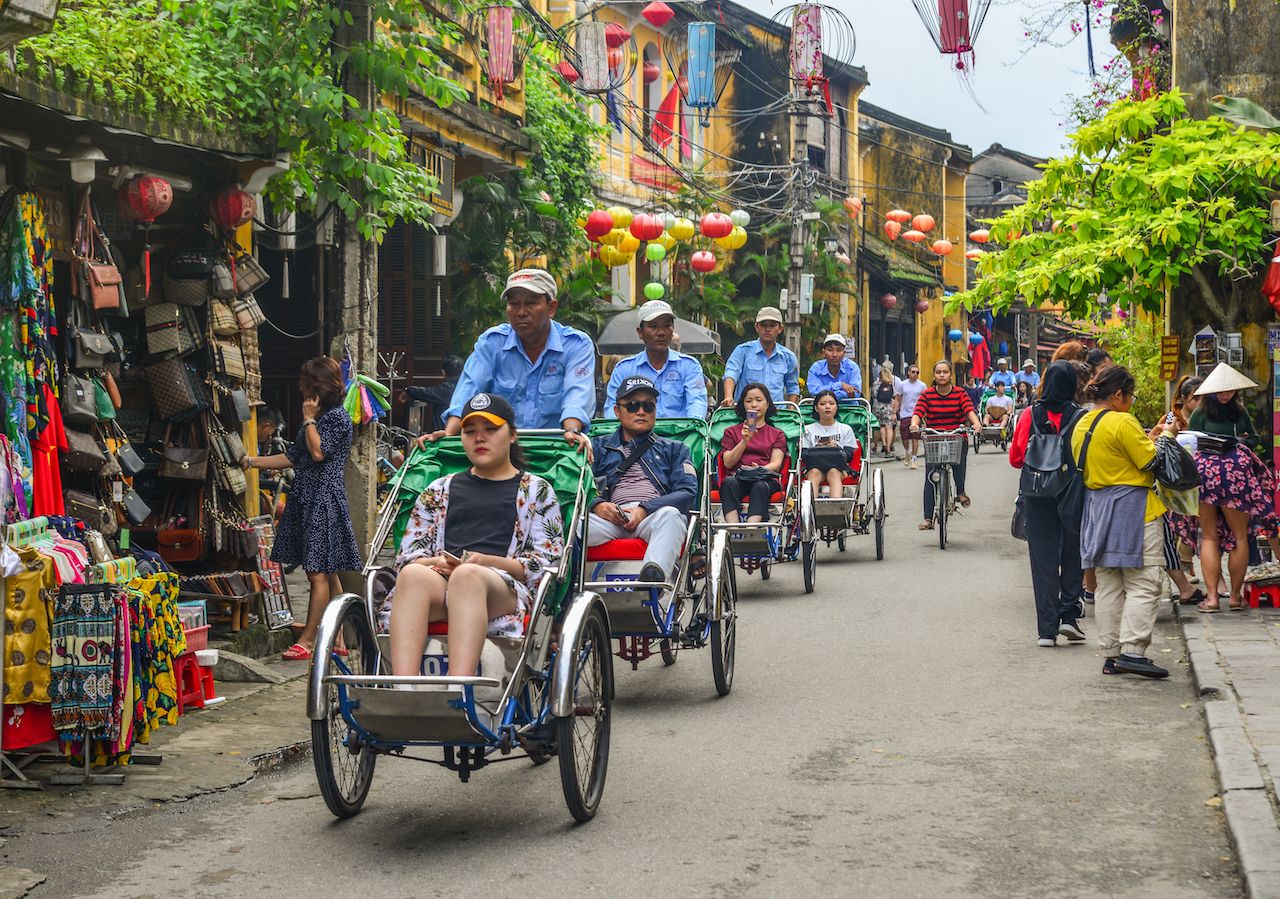 Cyclo (traditional rickshaw) carrying tourists in Hoi An, Vietnam