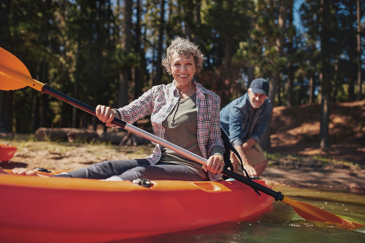 Portrait of happy senior woman in a kayak holding paddles