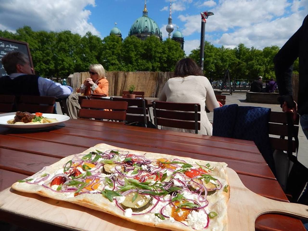 Table with flatbread pizza in front of Berlin landmark