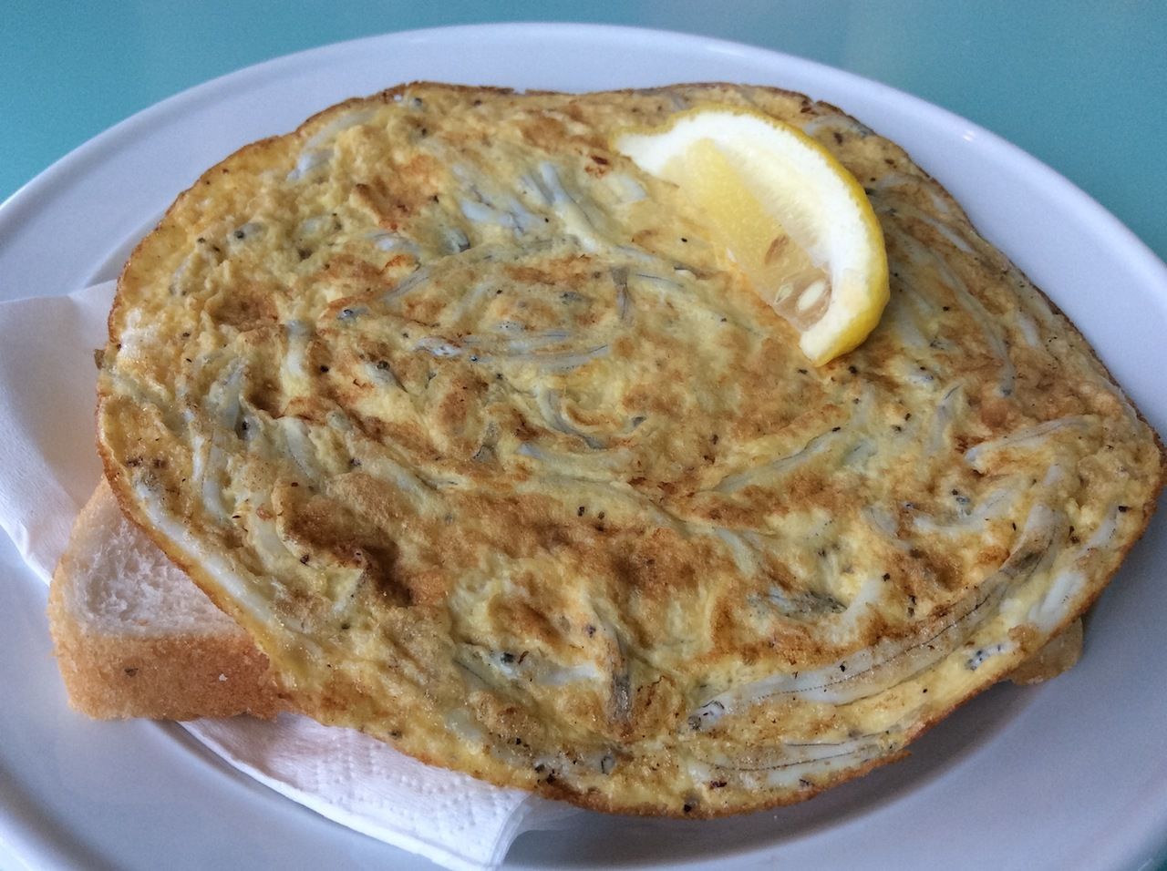 Whitebait fritter with bread and lemon wedge in New Zealand