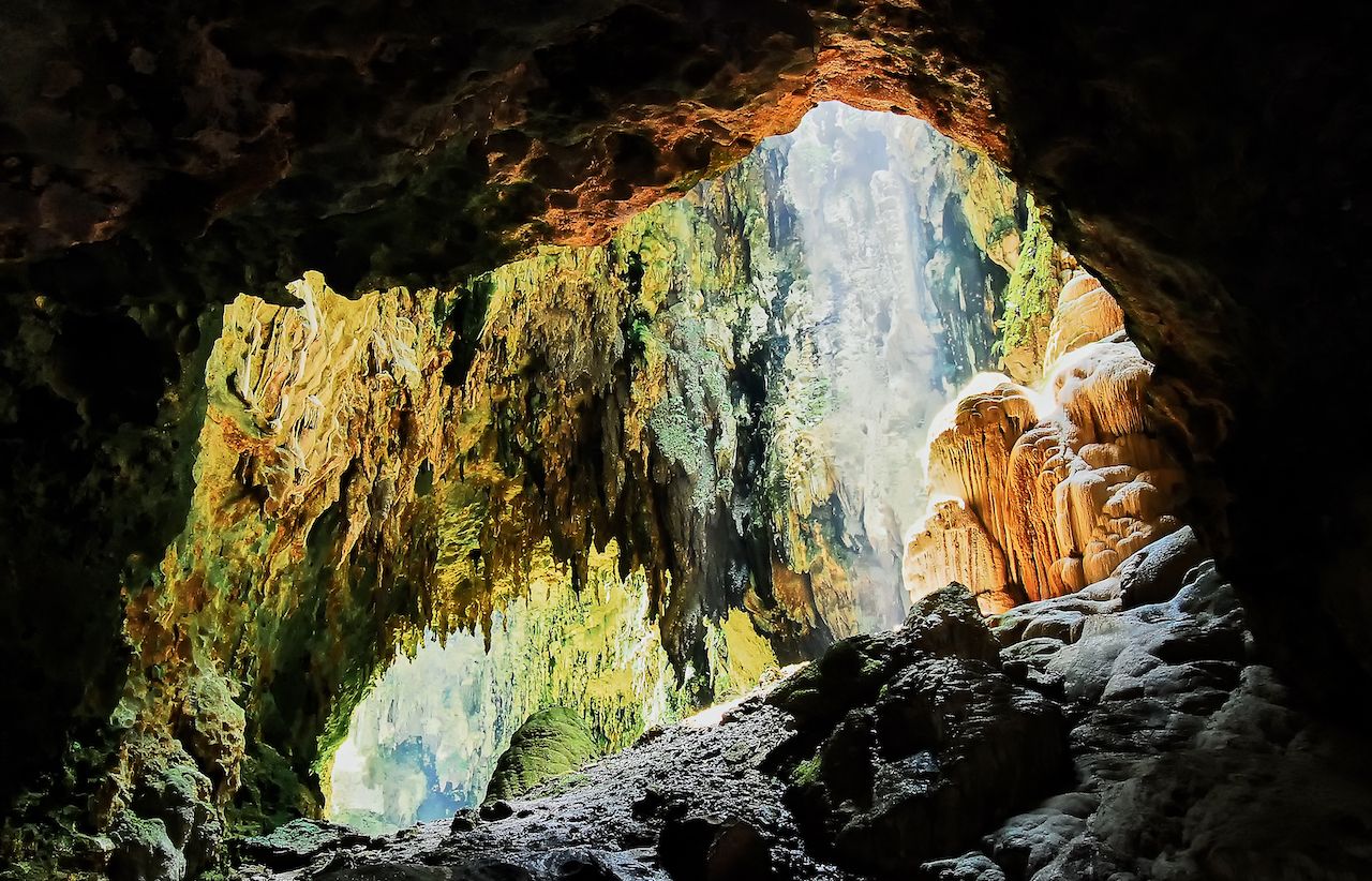 View into one chamber of the limestone Callao Cave with sunlight entering from the rooftop