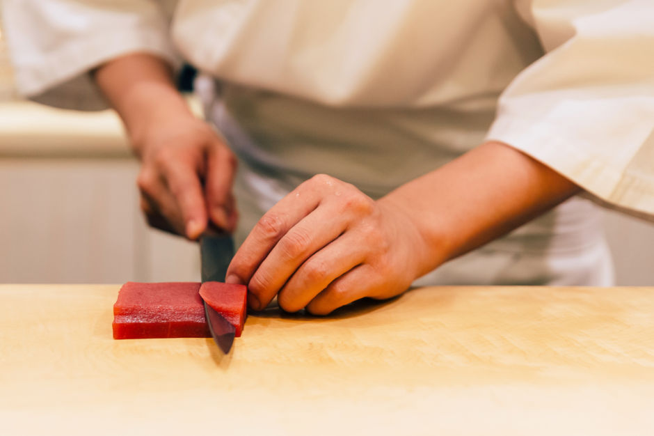 Japanese Omakase Chef cut bluefin tuna (Otoro in Japanese) neatly by knife on wooden kitchen counter for making sushi. Japanese luxury meal.; Shutterstock ID 1431476486; Purchase Order: ANA 2019 SP1
