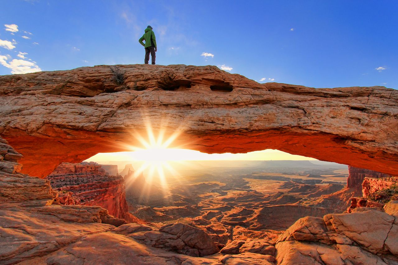 Silhouetted person standing on top of Mesa Arch, Canyonlands National Park, Utah